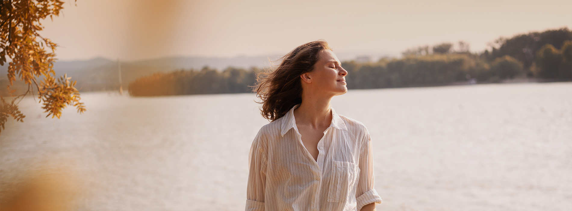 A person is seated in a dental chair, receiving care from a dental professional who stands behind them.