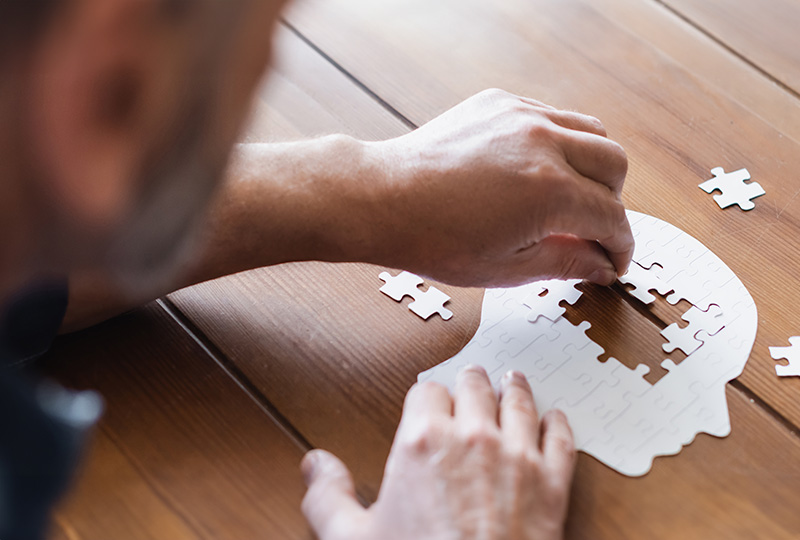 A person s hands are putting together a jigsaw puzzle on a table, with a close-up view of the puzzle pieces.