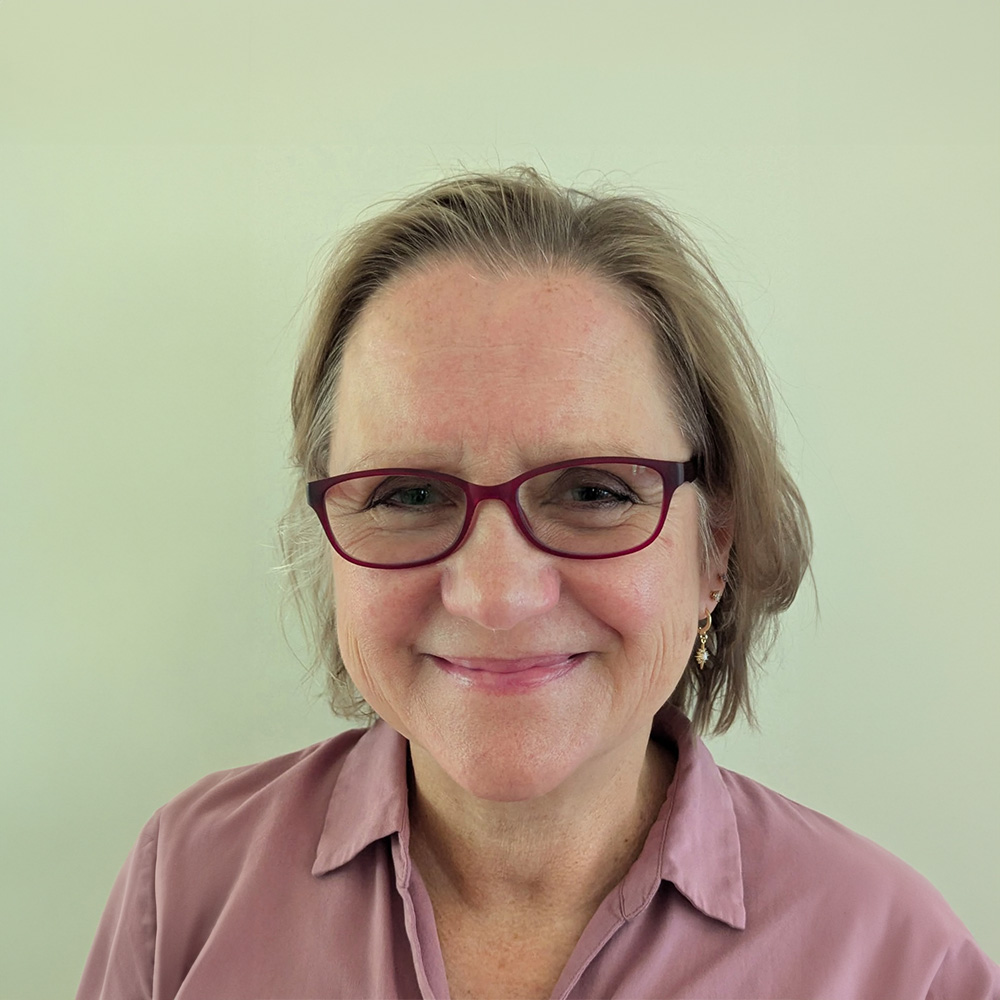 A woman with glasses smiling at the camera.