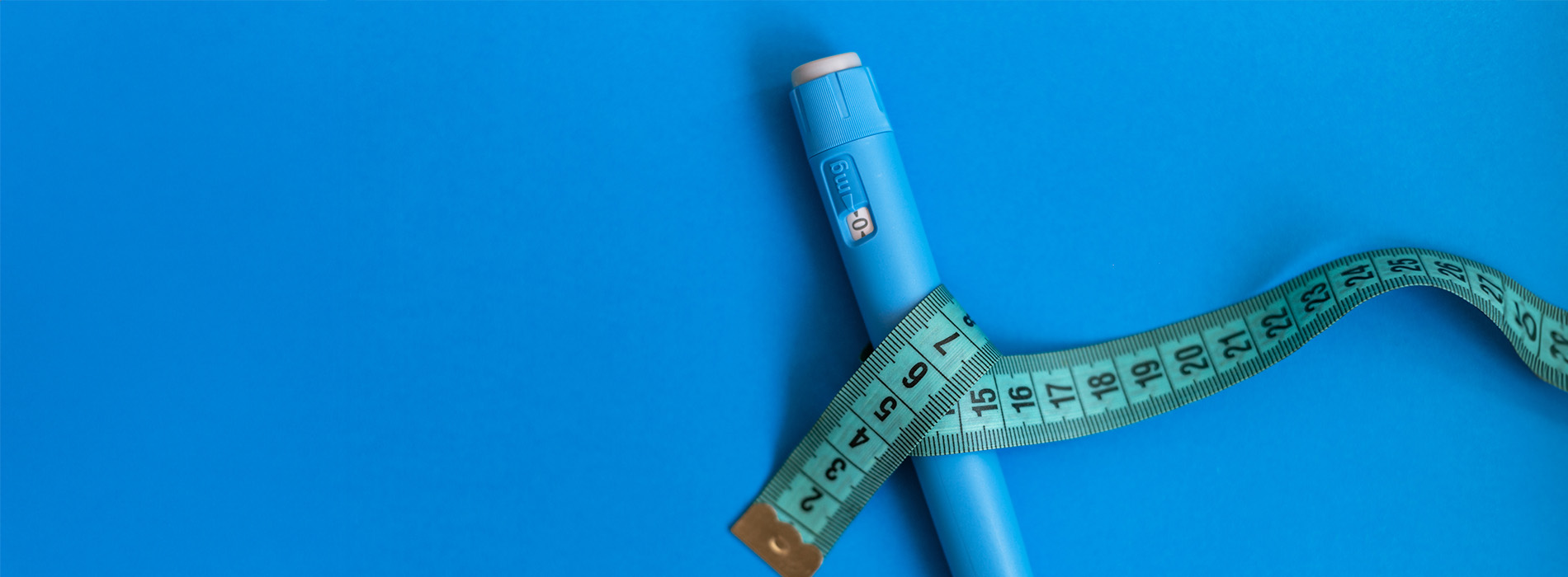 The image shows a blue measuring tape with a small object resting on it.